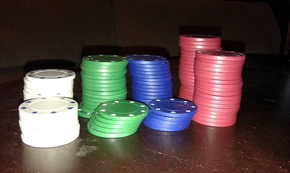 Coloured casino chips stacked on a table, illustrating baccarat house edge - baccarat banker vs player odds