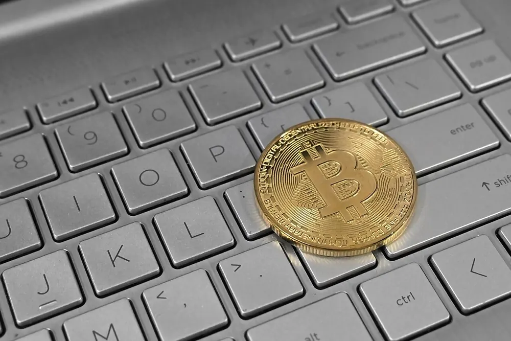Gold bitcoin coin on a laptop keyboard, illustrating crypto withdrawal fees - cloudbet minimum withdrawal