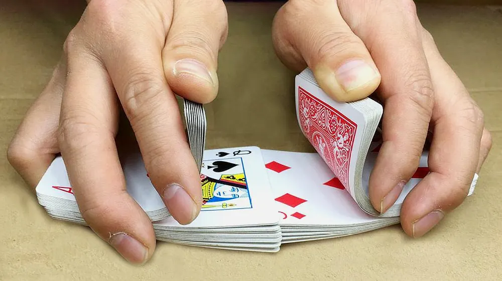 Hands riffle-shuffling a deck of playing cards - lucky 9 rules 4 players