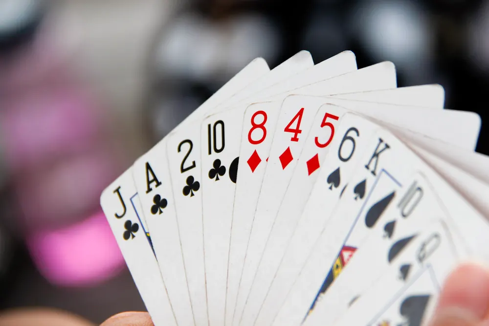 lucky 9 vs baccarat - Hand holding a fan of playing cards, as in a Lucky 9 or baccarat hand