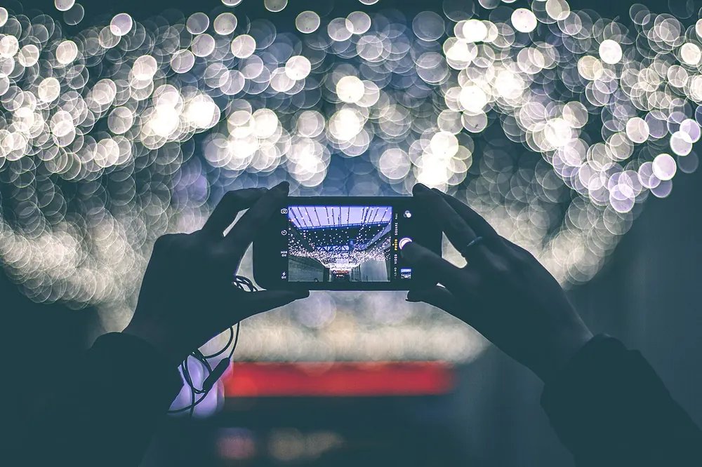Hands holding a smartphone horizontally against blurred lights, like a mobile gamer - mpl ph odds