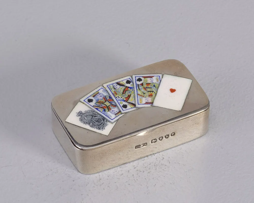 Playing cards fanned on top of a metal card box - pusoy dos rules