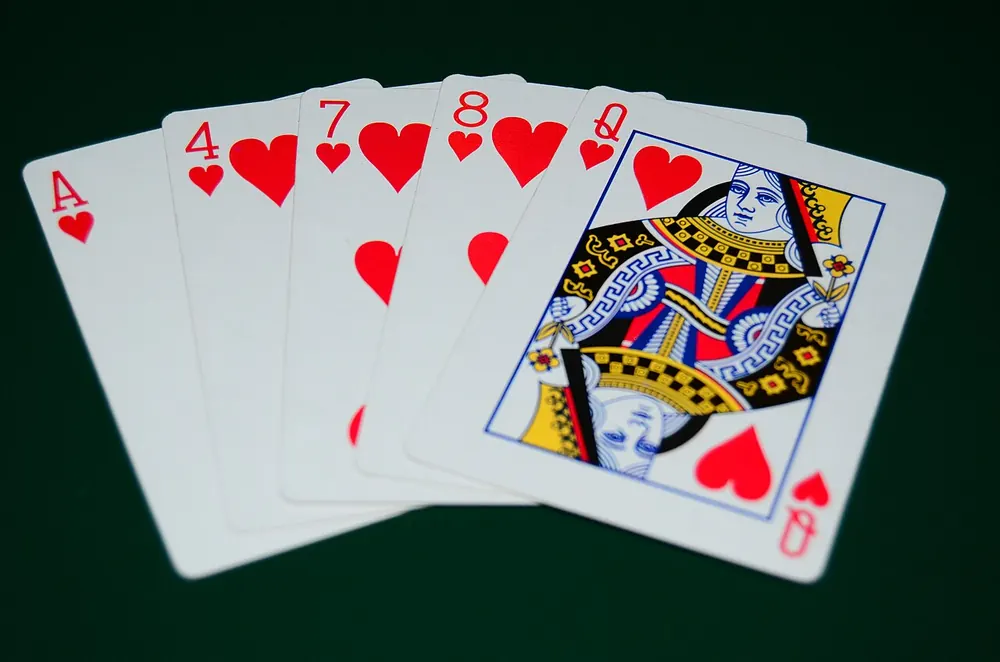 pusoy rules - Five-card poker hand of hearts on green felt