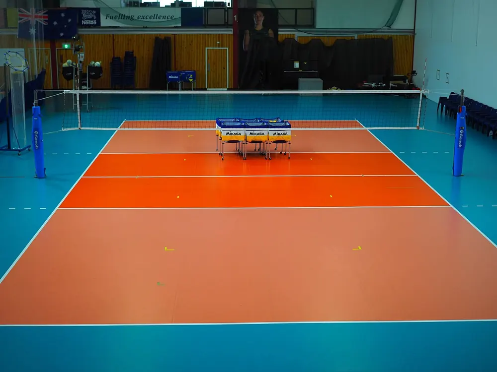 Empty indoor volleyball court with net, used to explain men's volleyball sets and totals - spikers turf betting