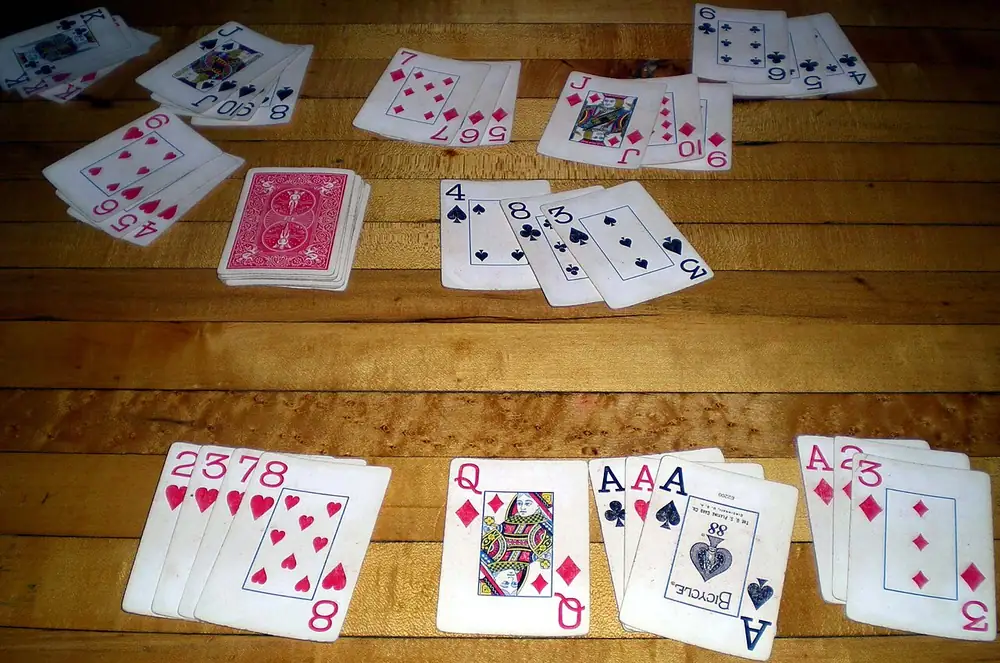 tongits rules - Rummy melds of playing cards laid out on a wooden floor