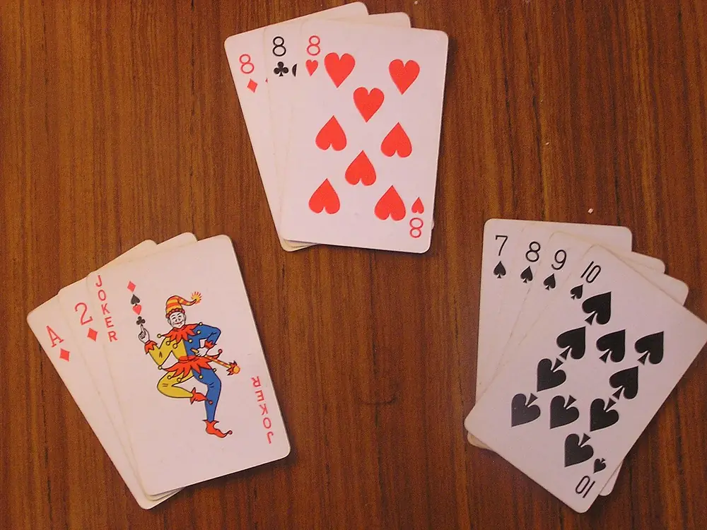 Three playing cards on a wooden table - tongits rules