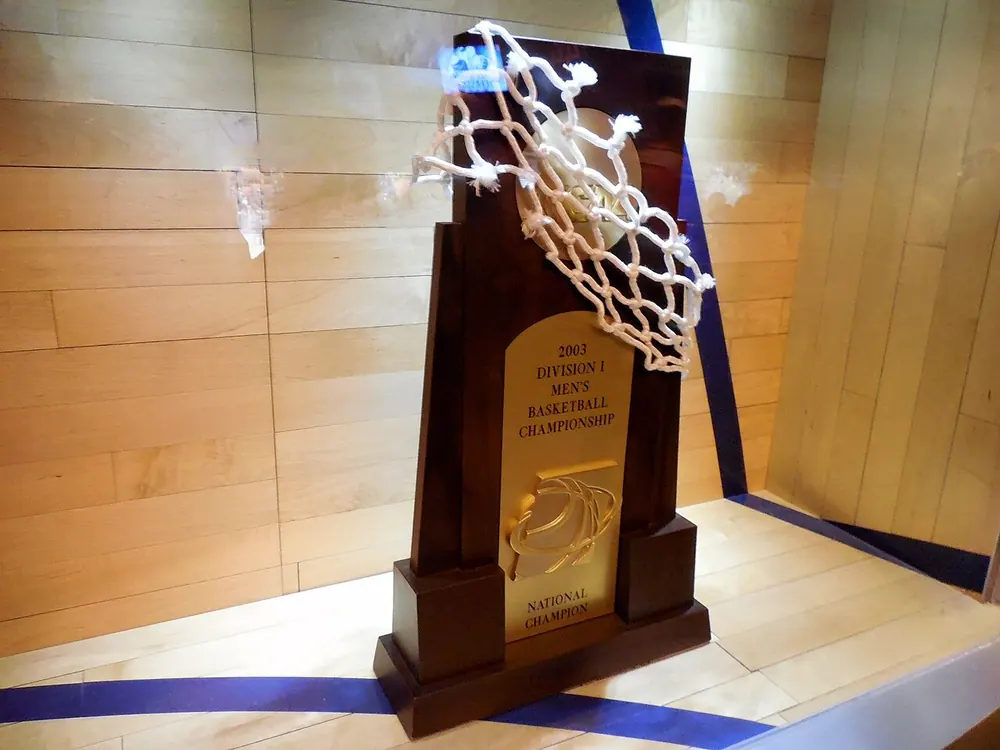 Basketball championship trophy draped with a cut-down net - uaap finals odds