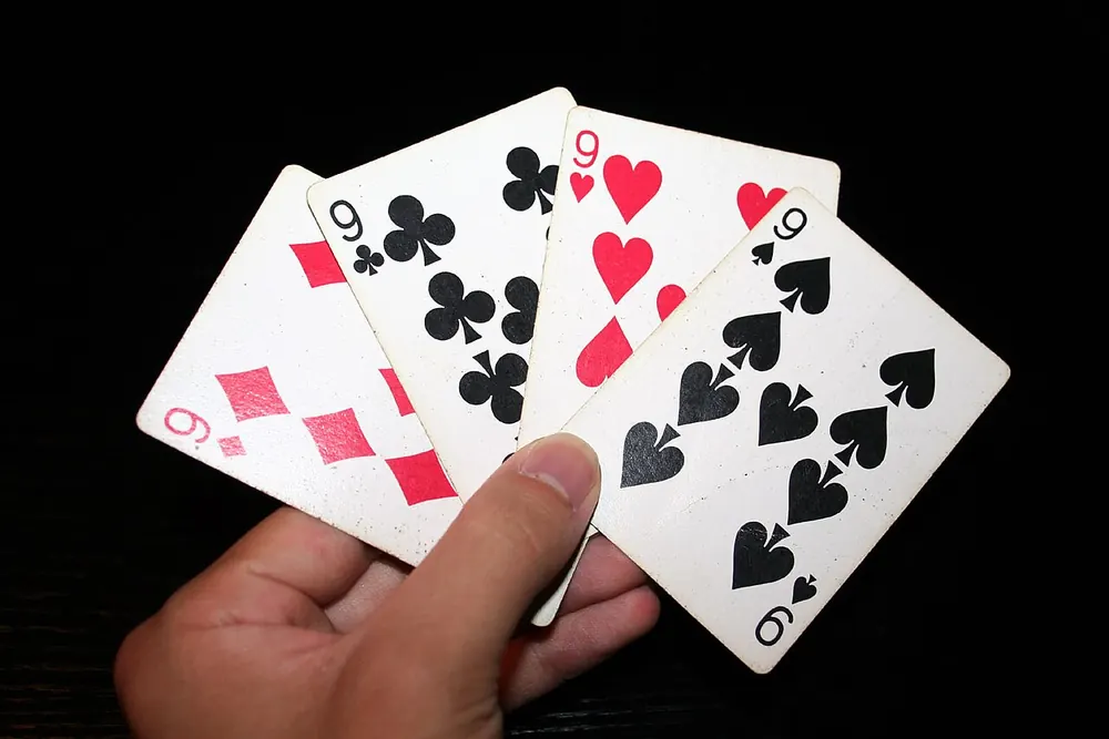 what is lucky 9 - Hand holding a fan of playing cards including nines